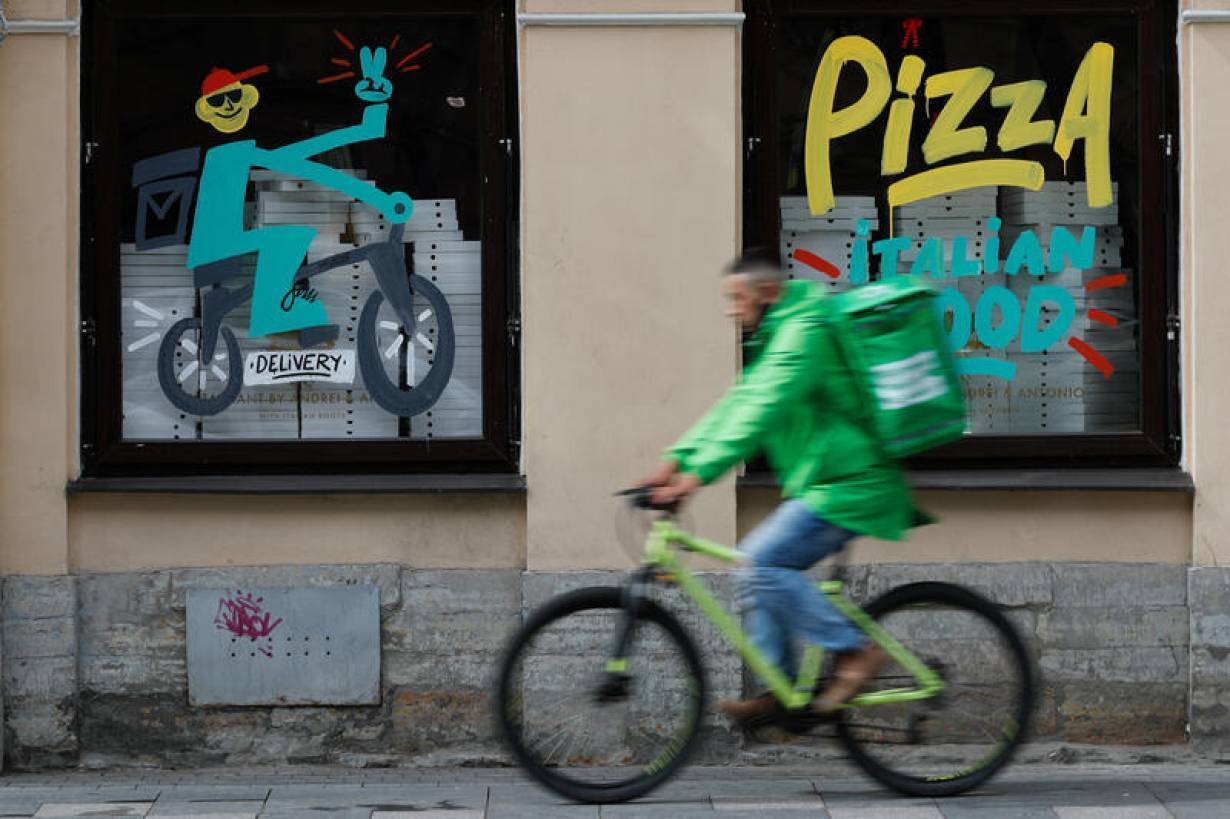 FILE PHOTO: A delivery person rides a bicycle past a restaurant, amid the outbreak of the coronavirus disease (COVID-19) in Saint Petersburg, Russia June 5, 2020.