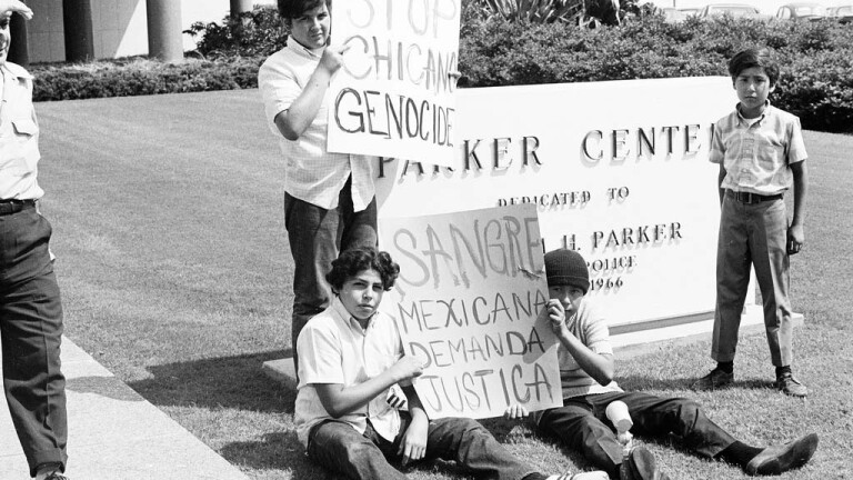 CSRC_LaRaza_B5F2C1_RR_022 Young men protest in front of Parker Center, the headquarters of the LAPD. | Raul Ruiz, La Raza photograph collection. Courtesy of UCLA Chicano Studies Research Center