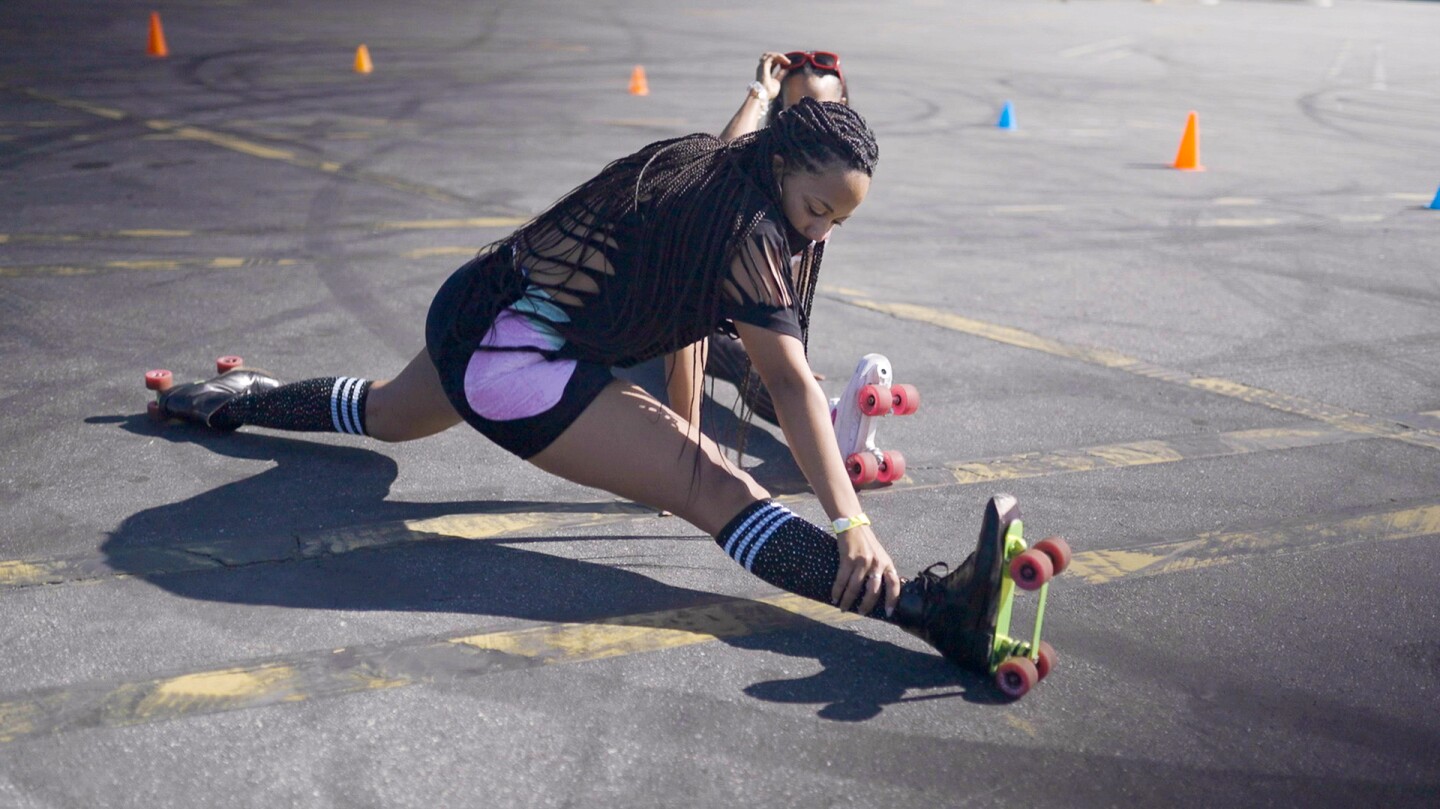 A young woman does a split with roller skates.