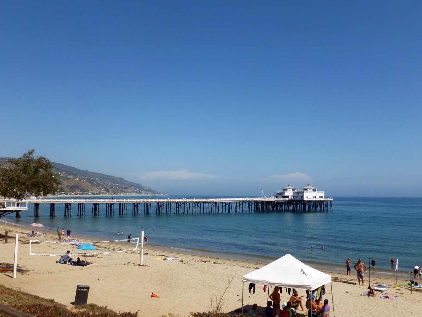 Malibu Pier visitors walk around the beach sand.