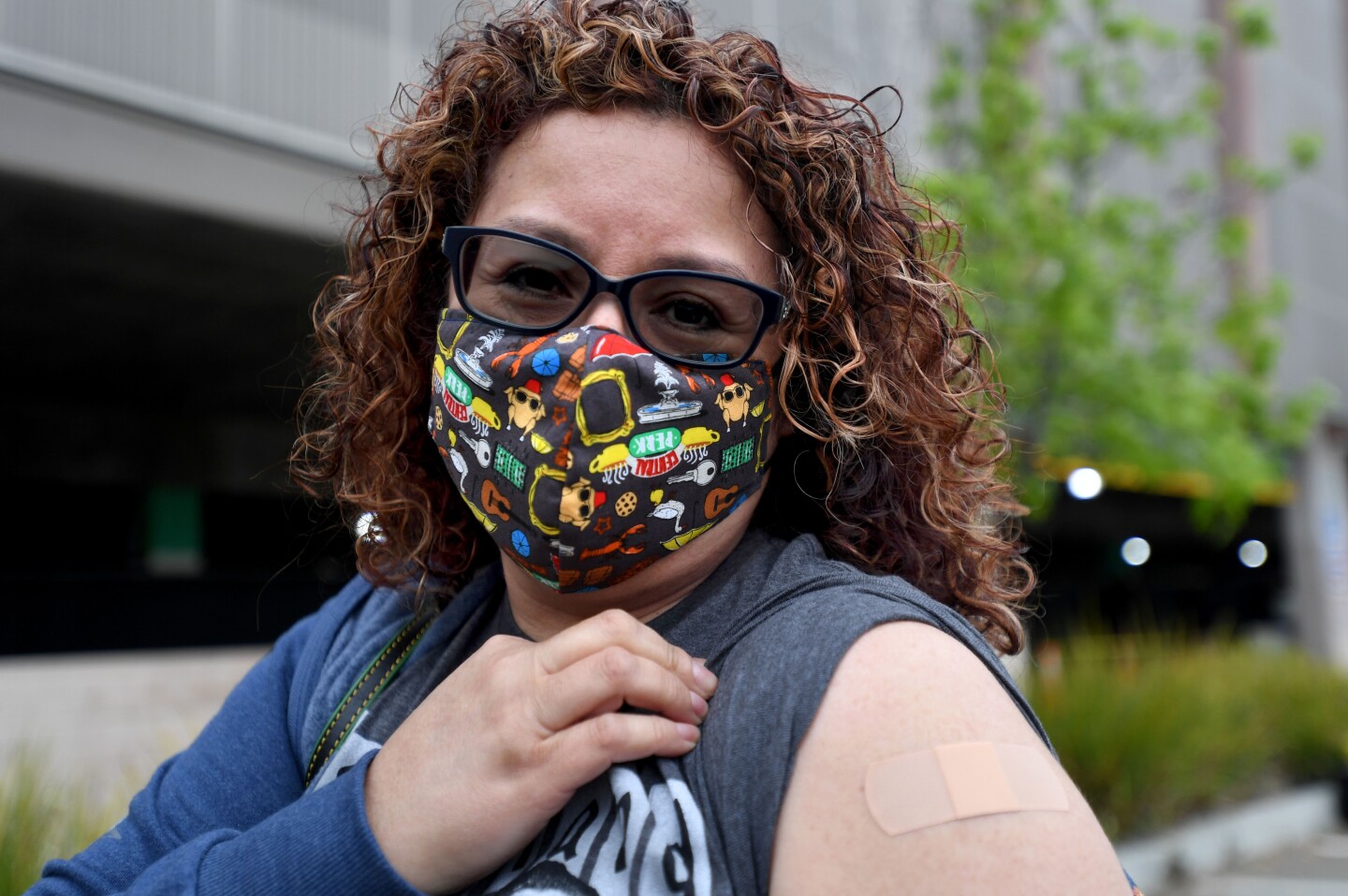 Darlene Toledo rolls up her left sleeve to show off her bandage where she got her COVID-19 vaccine.