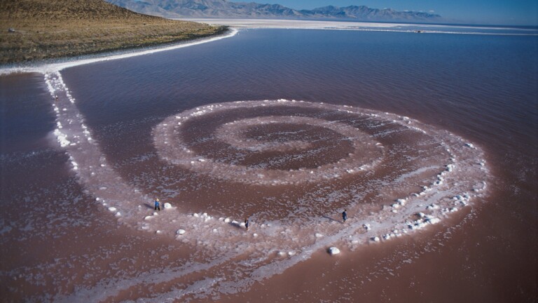 A view of Robert Smithson's land art called "Spiral Jetty" made primarily of black basalt rocks and salt crystals.
