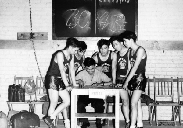 Chinese members of the Cathay basketball club gathered around Louie Lee, scorekeeper. They are playing the Wah Kue basketball team. | Harry Quillen Collection, Los Angeles Public Library