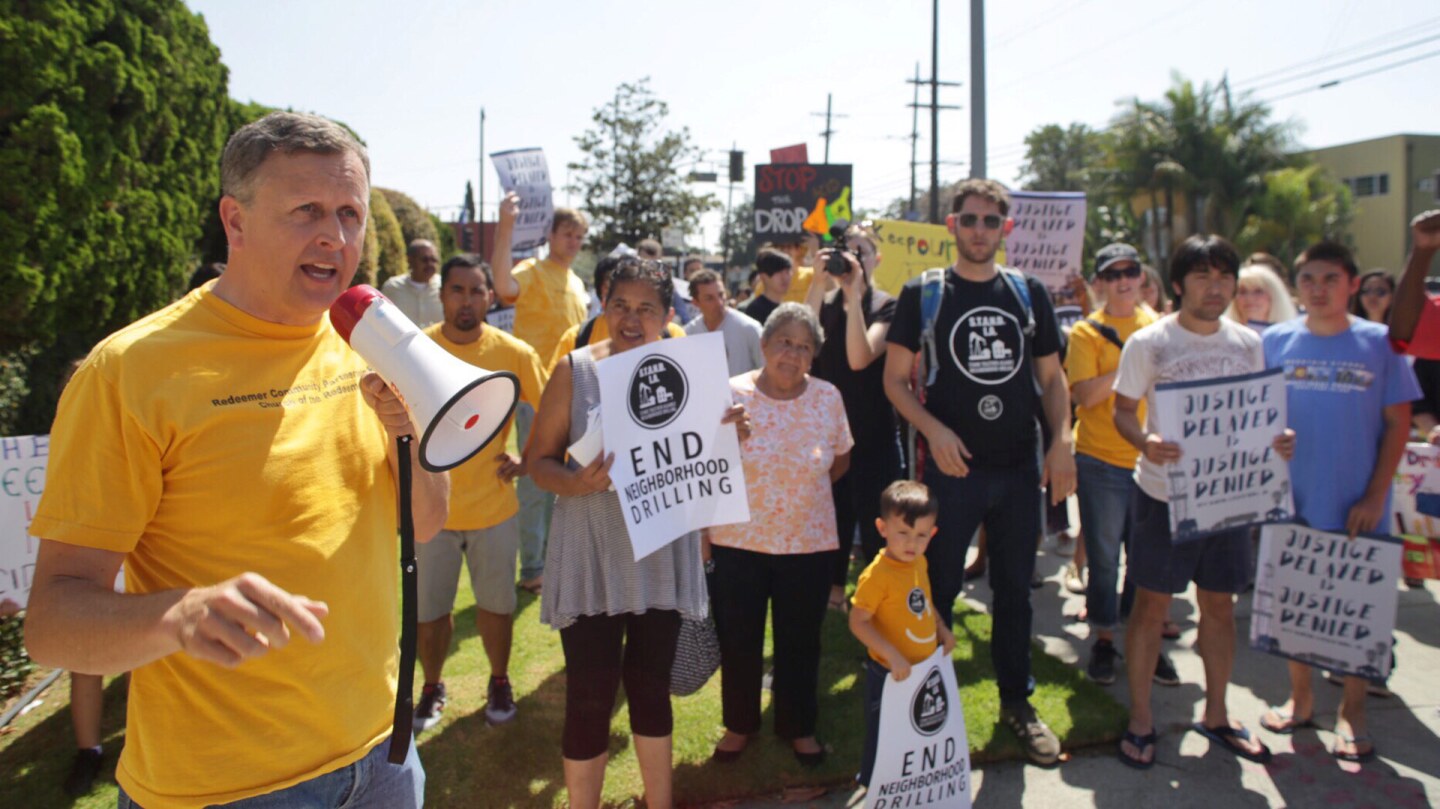 A group of people protest against neighborhood drilling.