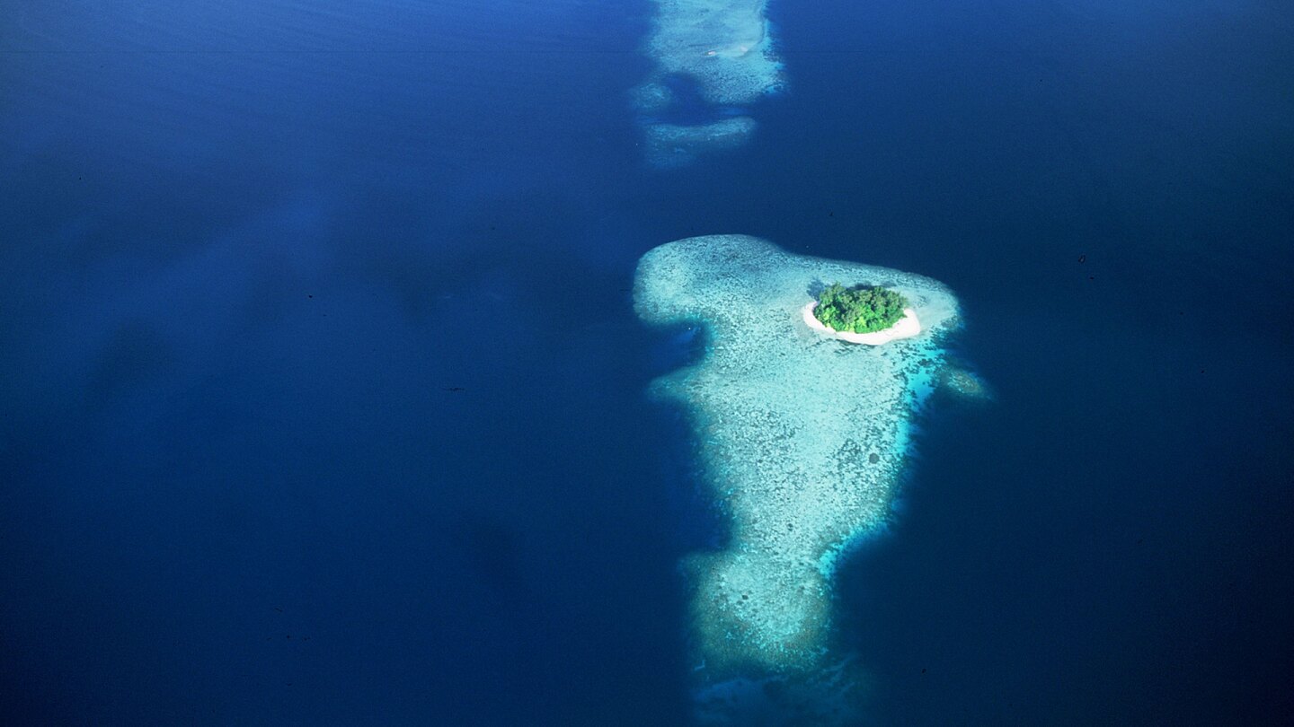 Overhead shot of an island in the middle of a vast ocean. | From "South Pacific."