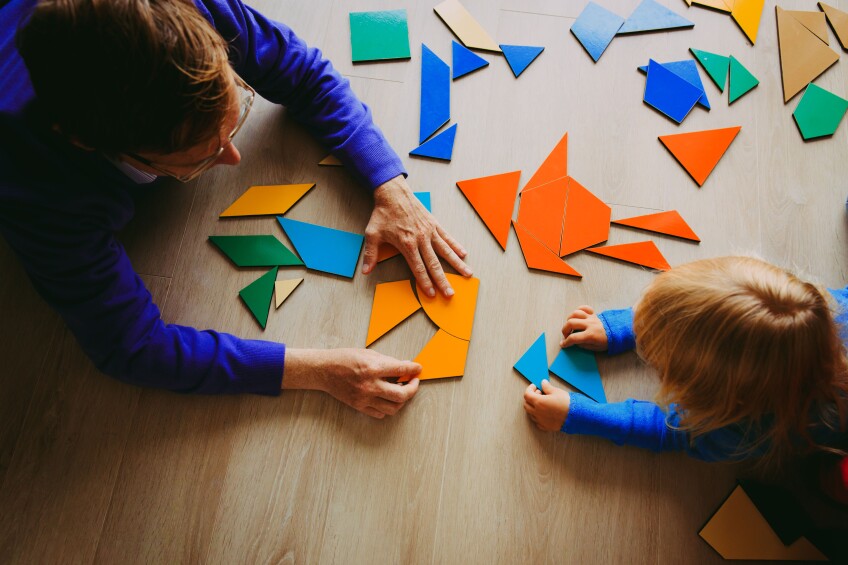 Una mujer y un niño juegan con figuras geométricas de varios tangrams.