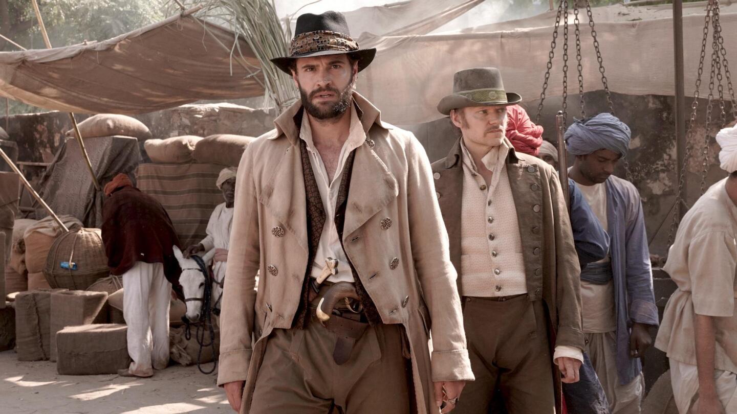 John Beecham (Tom Bateman) and Samuel Parker (Marc Warren) stand in a marketplace. | From "Beecham House on Masterpiece: Episode 1"