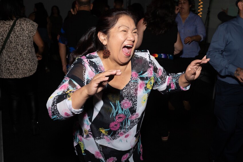 A lady in a flower shirt expresses joy at Cumbiatón.