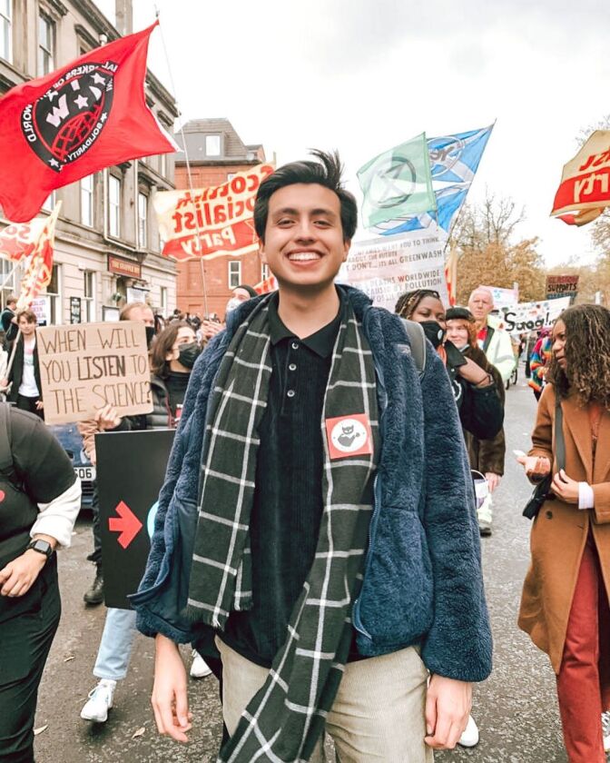 Isaias Hernandez smiles towards the camera as protesters march behind him