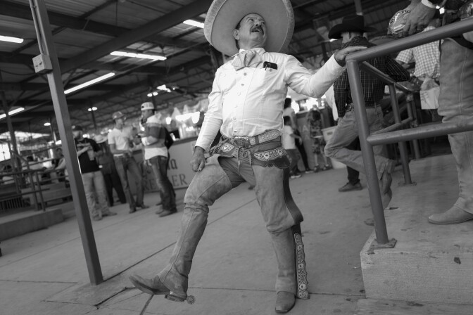 El hombre viste el traje completo típico de un charros: traje de charros, pantalón ajustado, chaparreras de cuero y sombreros de ala ancha.