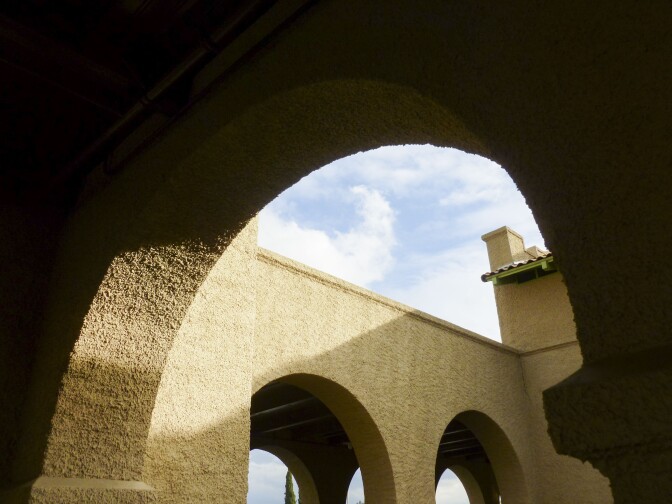 A shadowed archway on the train depot exterior offers a view of the blue sky and other parts of the building.
