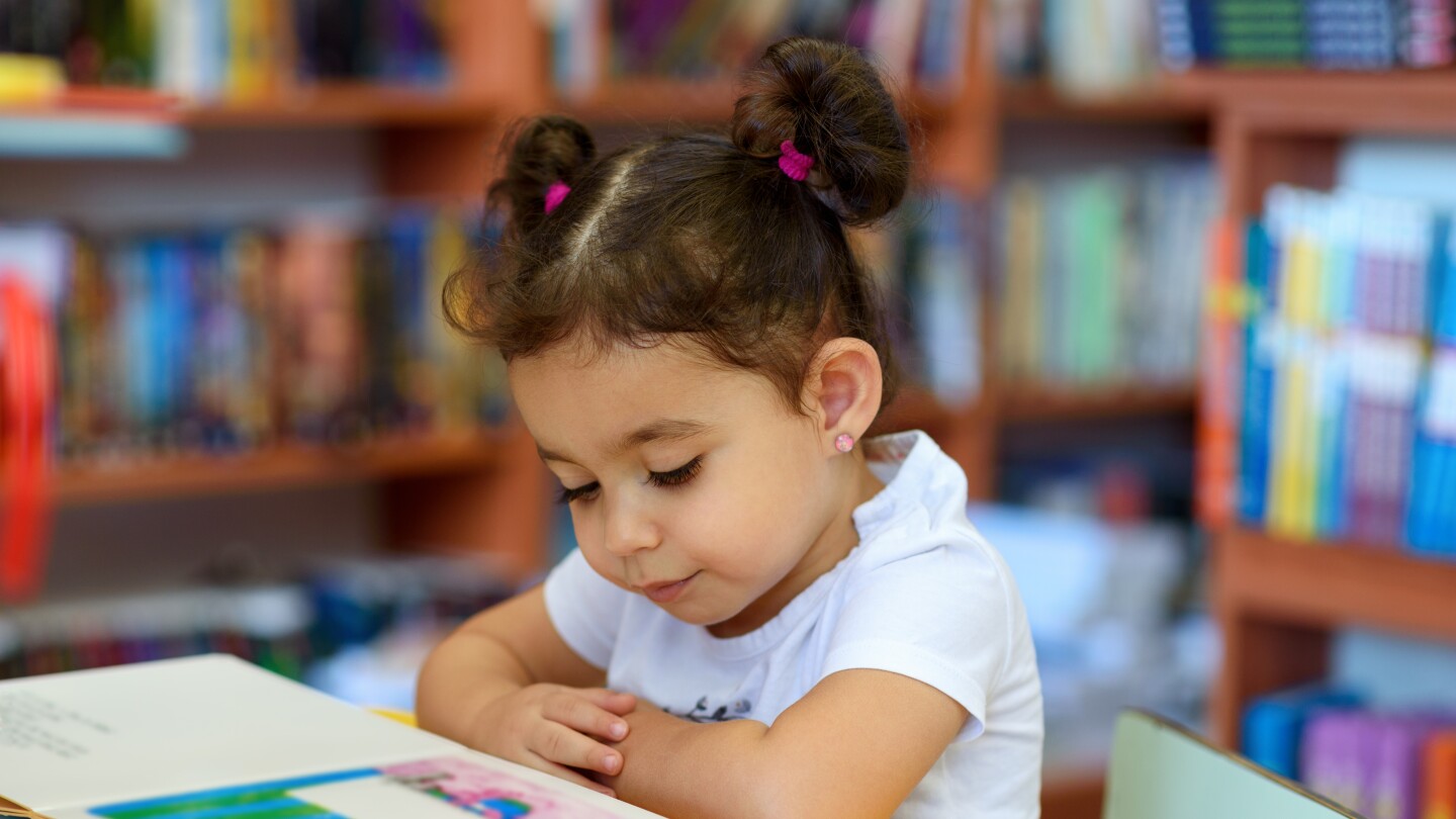 Happy child little girl reading a book.