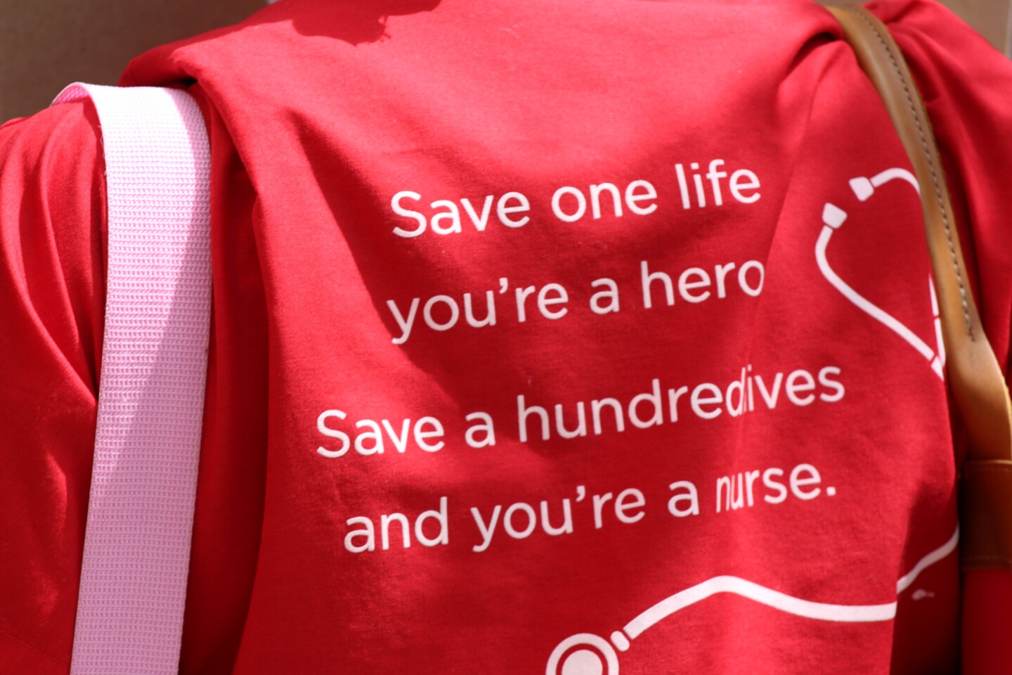 Back of someone's shirt reading, "Save one life, you're a hero. Save a hundred lives, you're a nurse" during protest on Friday April 3rd | Karen Foshay