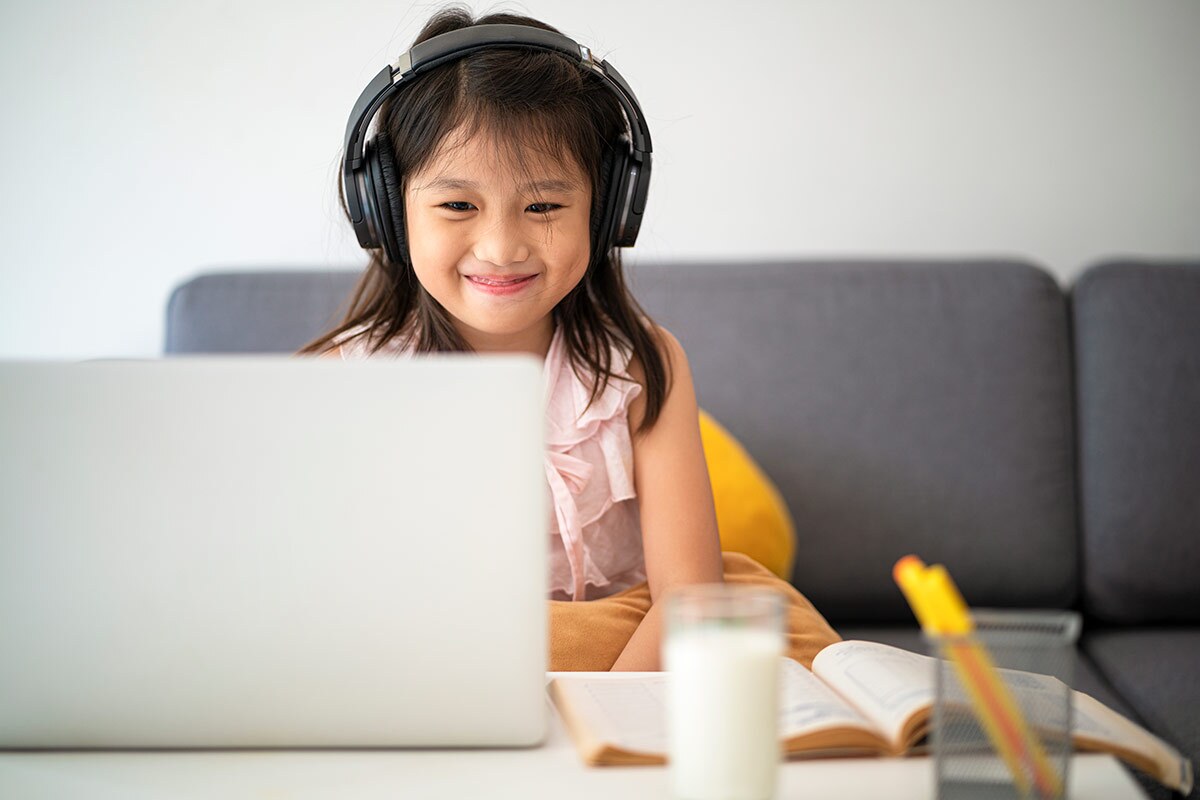A small child smiled as she works in front of a computer. | iStock