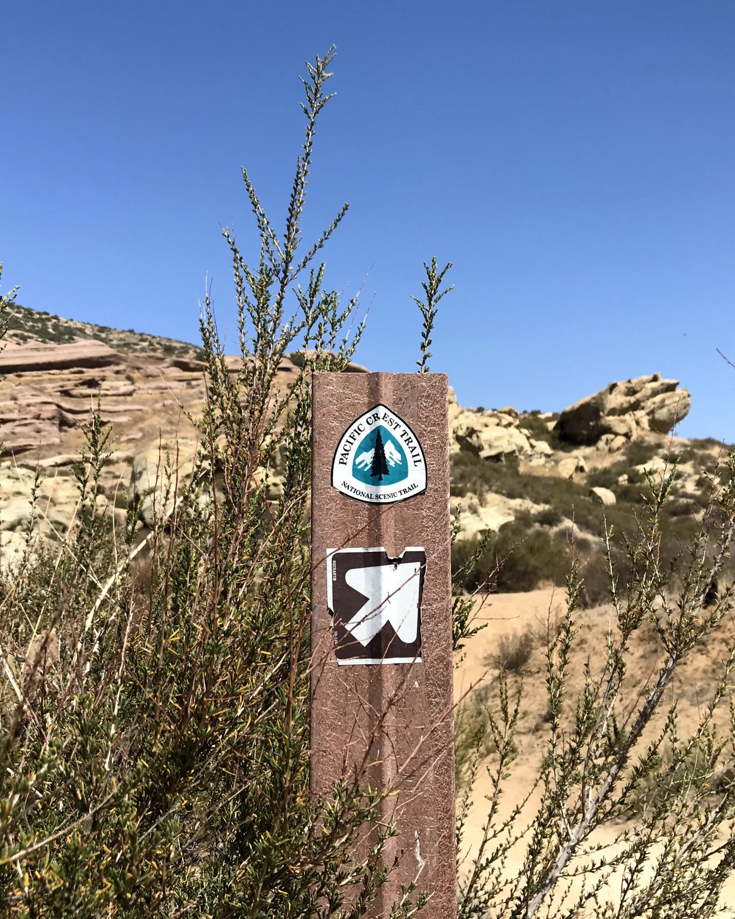 Pacific Crest Trail signpost against the sandstone rock landscape of Vasquez Rocks Natural Area Park.