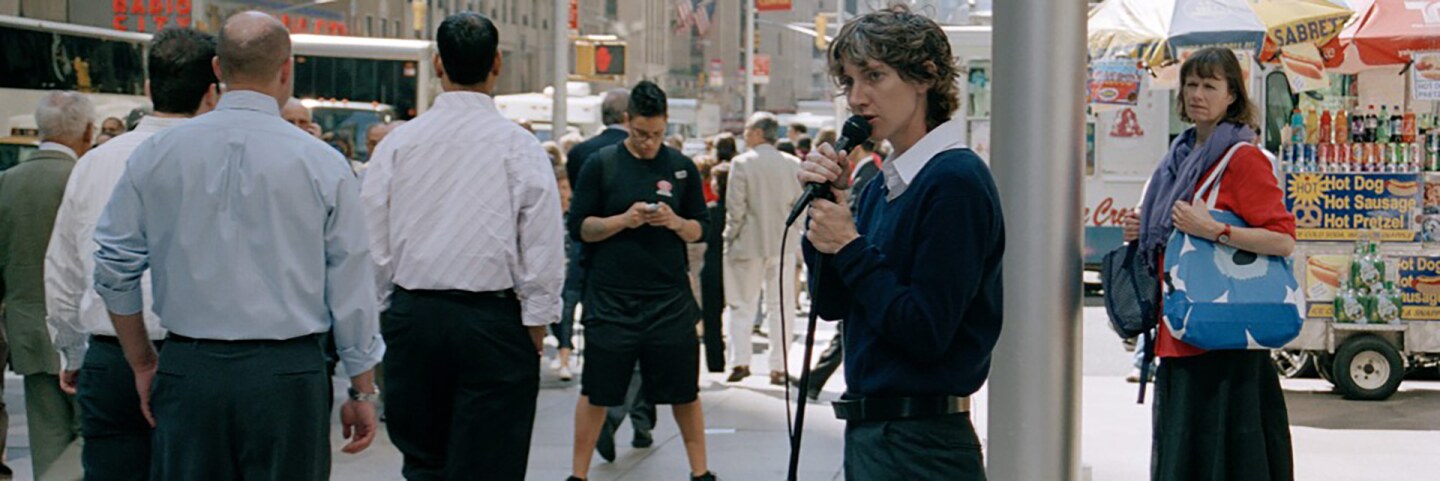 Sharon Hayes performs “Everything Else Has Failed! Don’t You Think It’s Time For Love?” (2007), a work staged on a Manhattan street corner where Hayes read texts directed to an anonymous lover. | Courtesy of UCLA