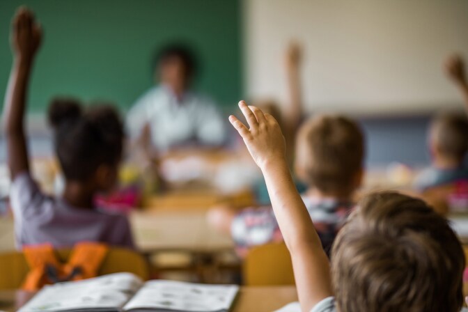 Varios niños levantan la mano en un aula.