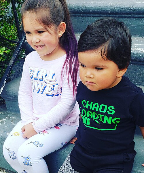 Two children smile as they sit next to each other. 