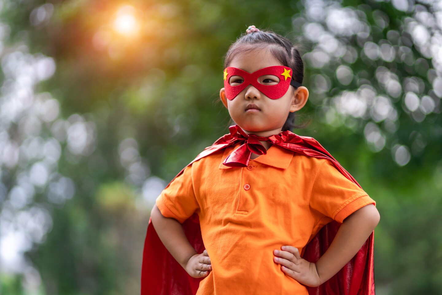 small Asian American child wearing a red mask and cape