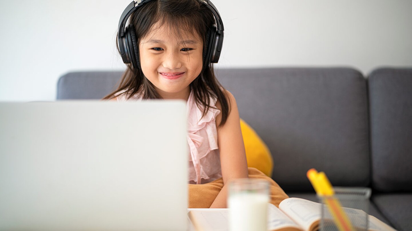 A small child smiled as she works in front of a computer. | iStock