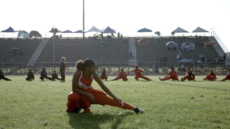 Girl in foreground stretching, with teammates stretching behind her | Still from "Born to Run", SoCal Connected