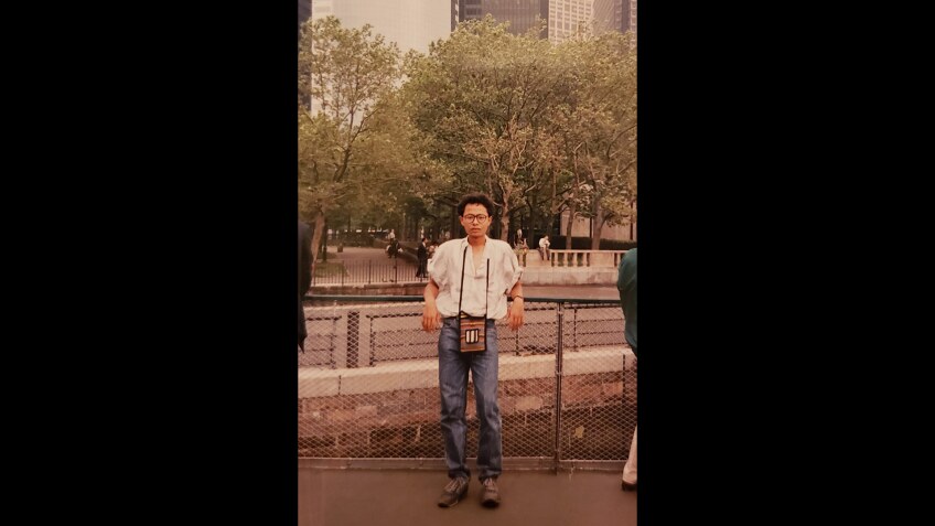 A man smiles while posing in front of a railing.