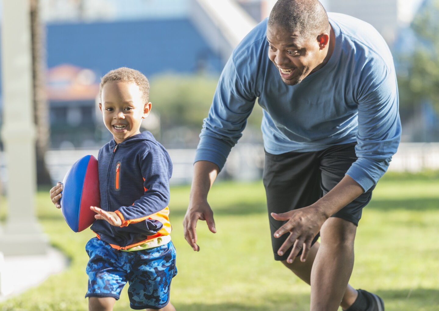 Little boy and father playing in the park with ball