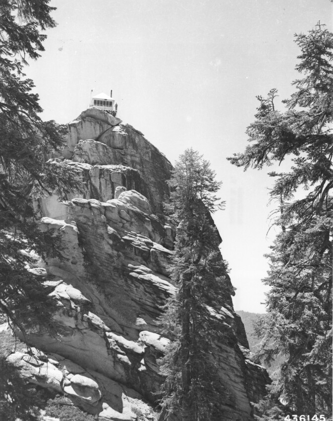 A fire tower sits atop a mountain.
