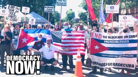 Demonstrators hold up Cuban flags and signs calling to end the Cuban blockade.