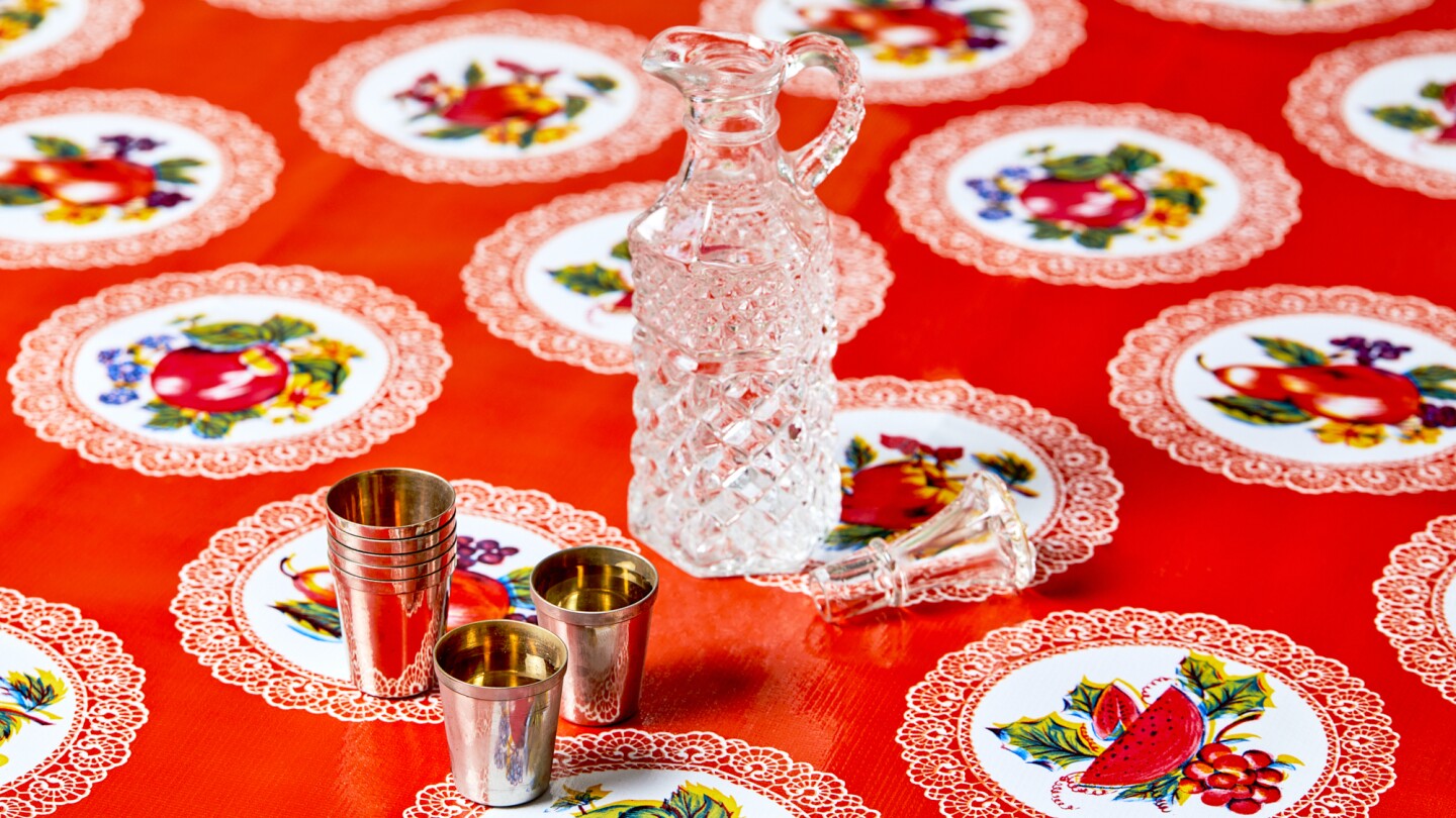 Clear vodka in a pitcher, pictured with metal cups.