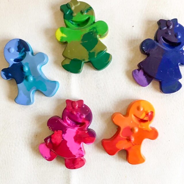 Five swirled crayons in the shape of gingerbread dolls in blue, orange, purple, pink and orange shades.