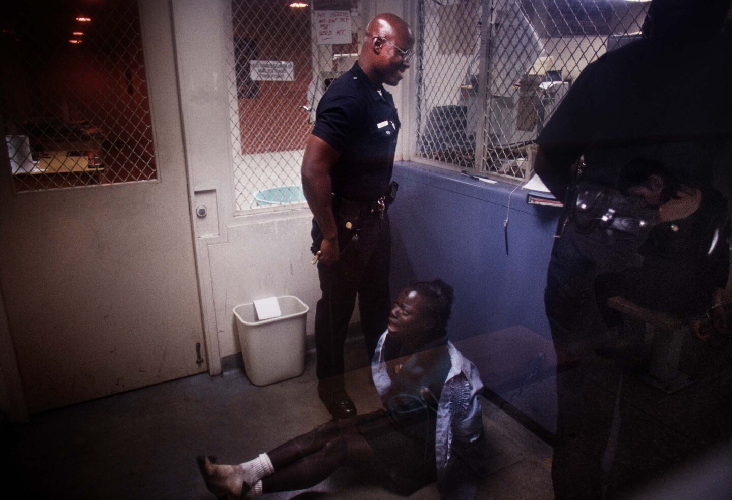 A handcuffed woman is detained and booked at Rampart Station. | Joseph Rodriguez
