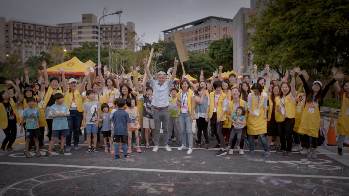 "Life-Sized City" host Mikael Colville-Anderson raises both his arms with an excited crowd.