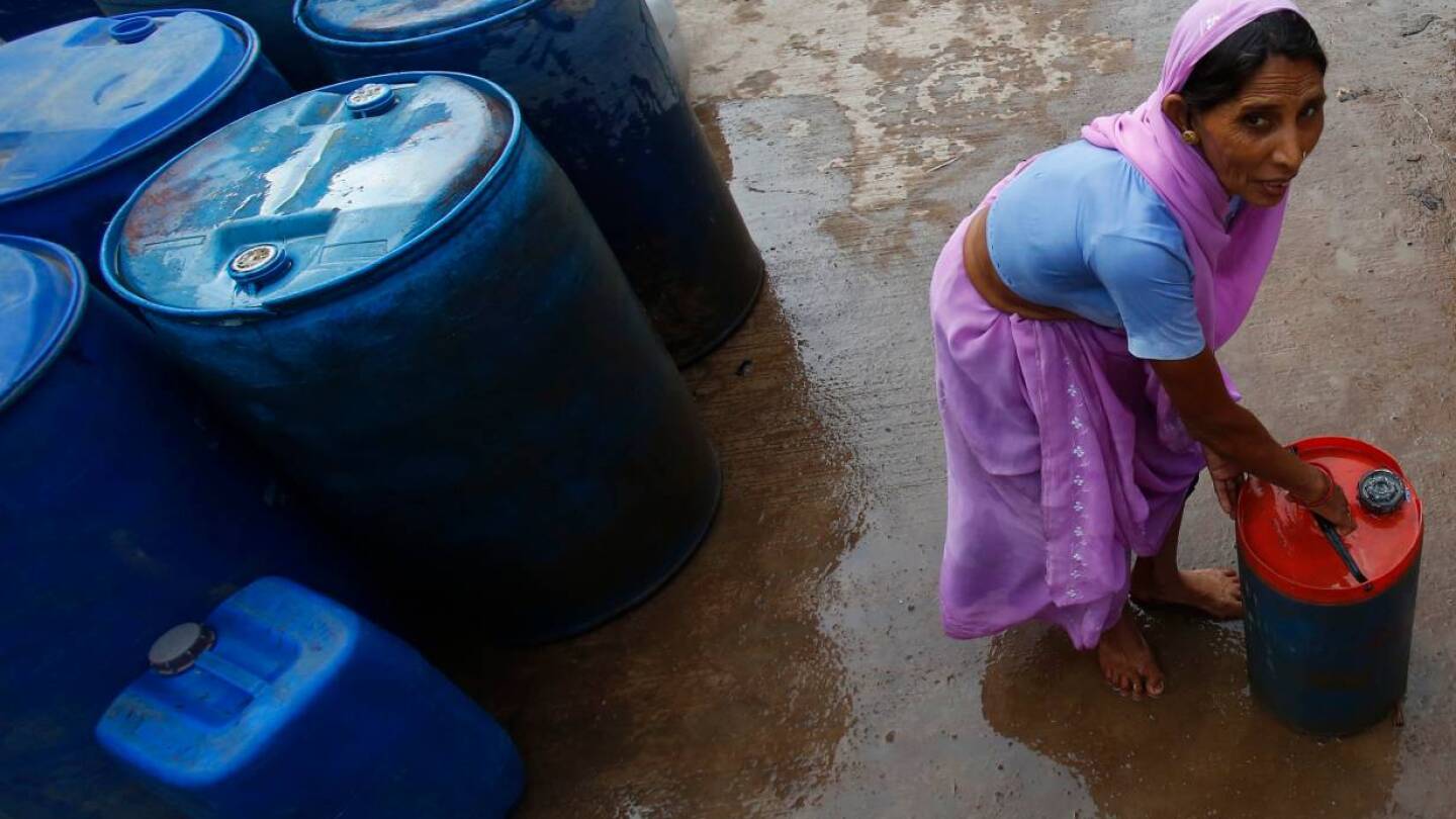 ARCHIVE PHOTO: A woman transports a drum after filling it with free drinking water supplied by a municipal corporation water tanker at a slum on a hot summer day in New Delhi June 16, 2014. | REUTERS/Anindito Mukherjee