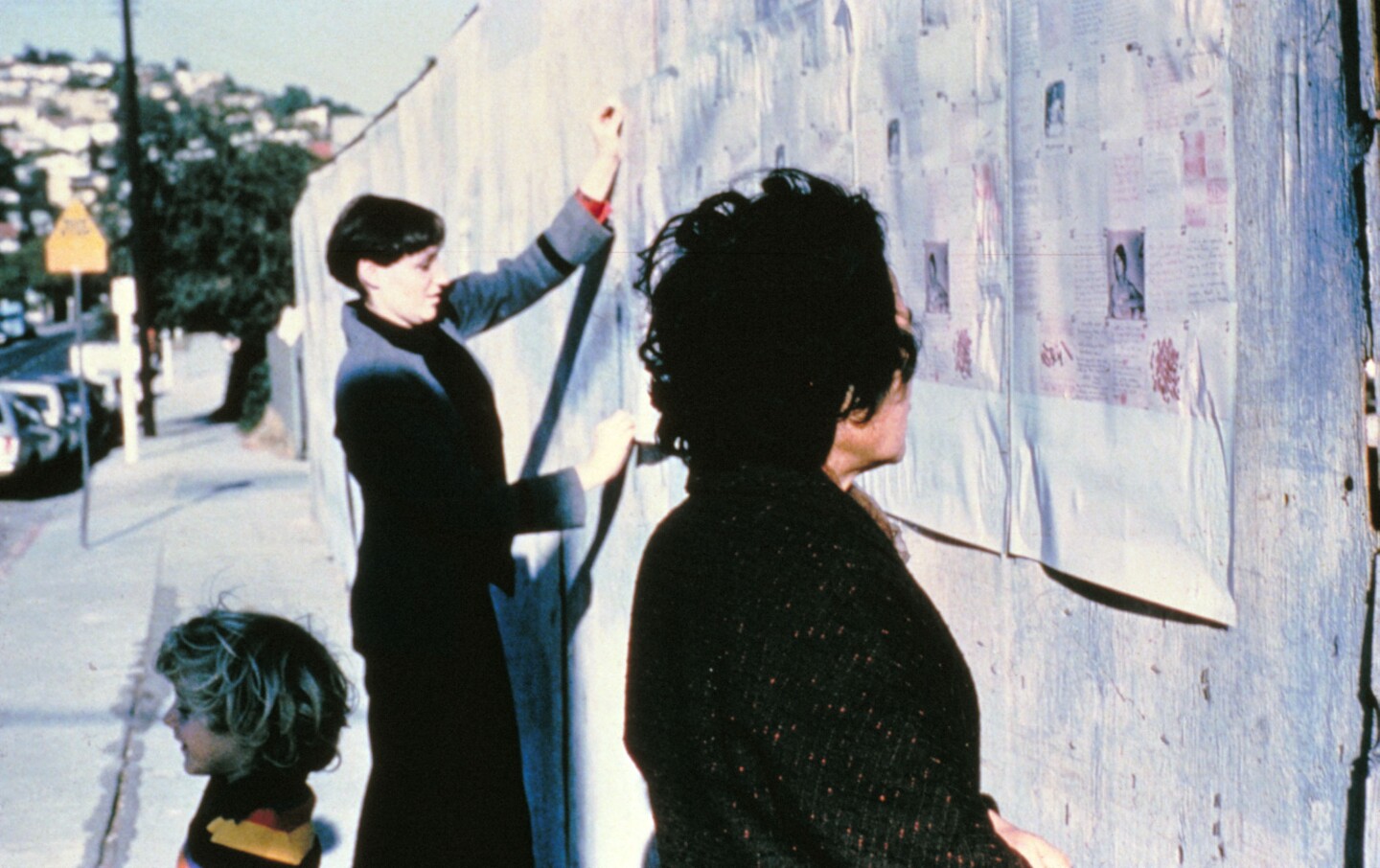 Designer Sheila de Bretteville hanging up her "Pink" poster in the streets.