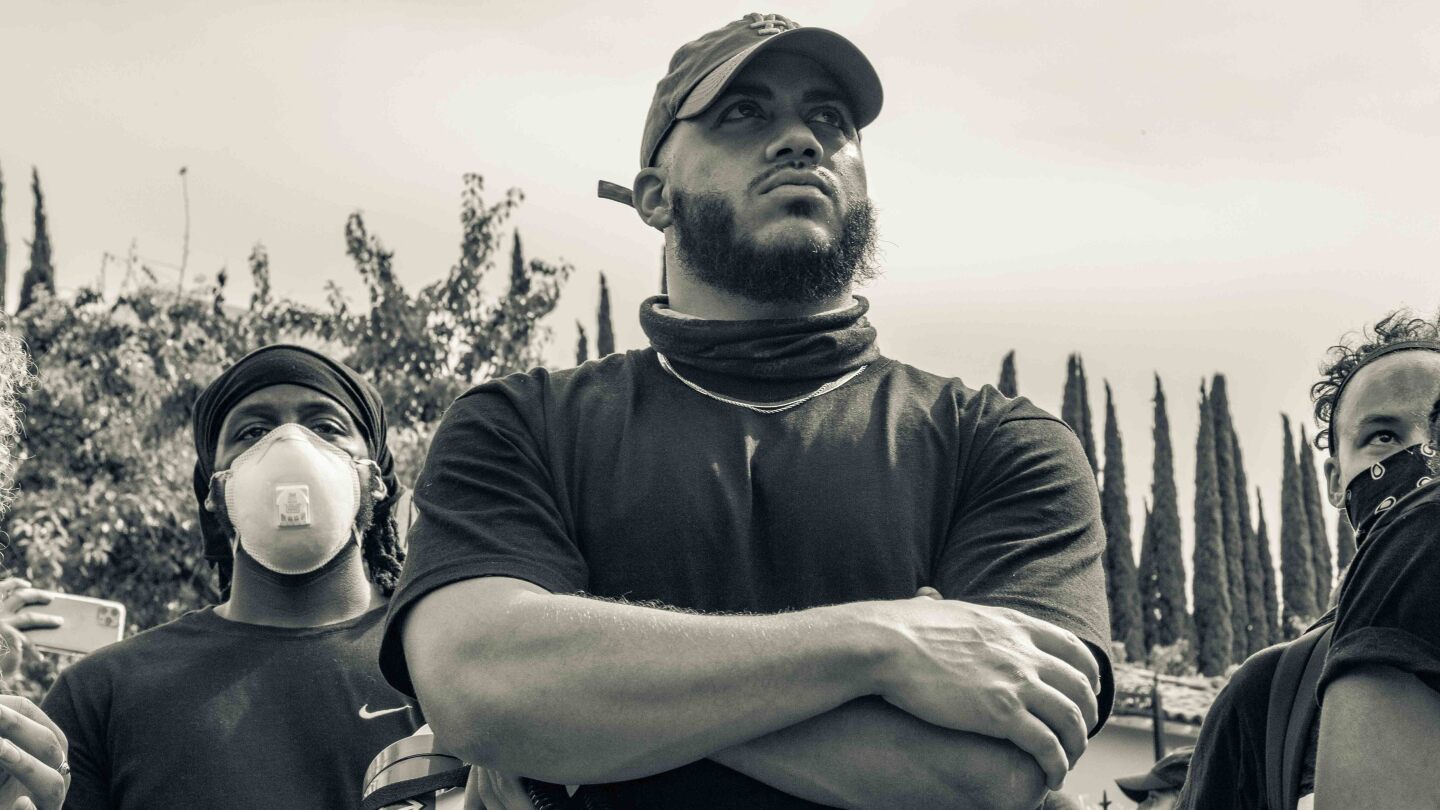 Issac Bryan stands arms folded, at a Black Lives Matter in June 2020 | Trevor Jackson