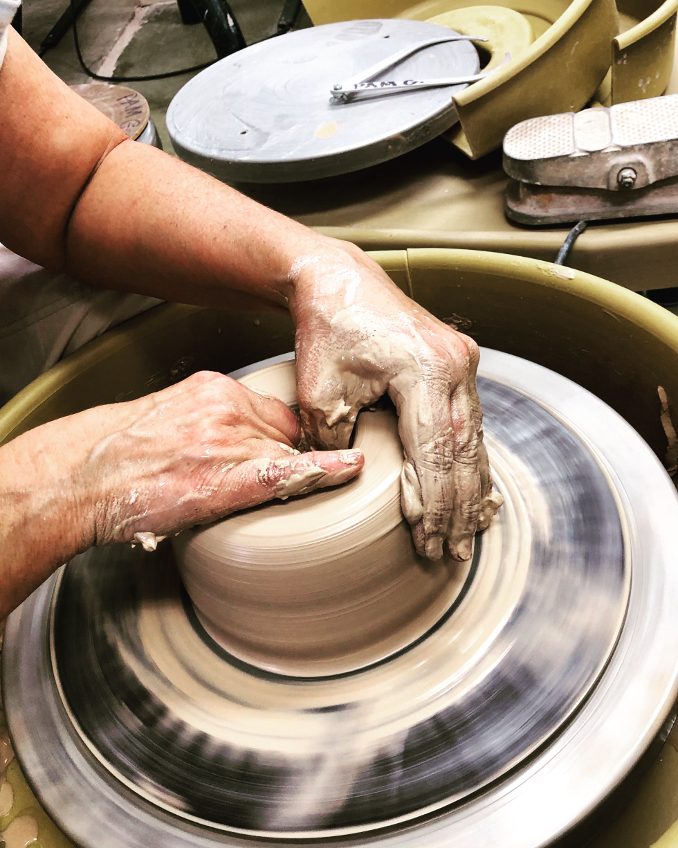 Two hands a centering clay on a potter's wheel.