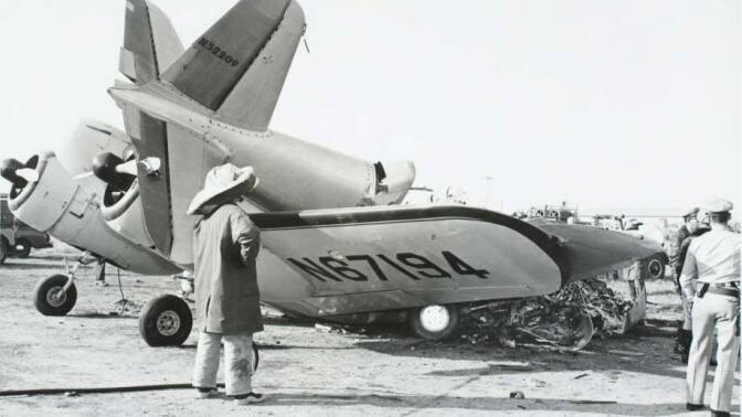 Small plane damaged by crash, with tail broken off and resting on wing. Cockpit and propellor remain intact. Firefighter in full-cover protective dress surveys scene with police officer near plane. | John J. Lloyd, Courtesy of CSUDH