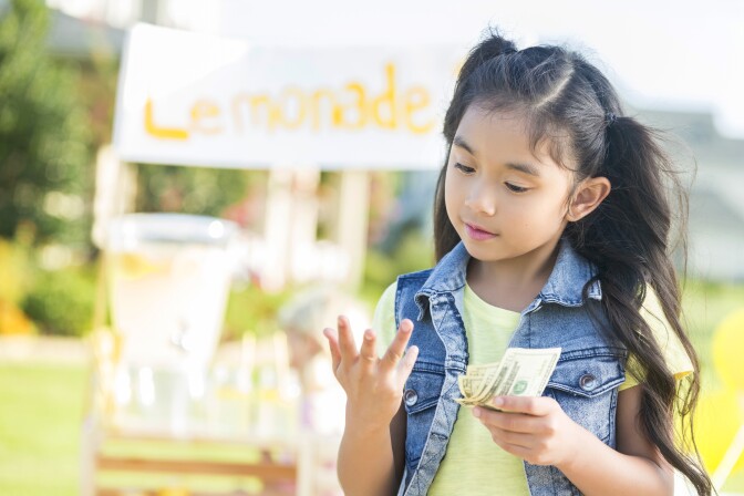 Young girl counts money made from lemonade stand
