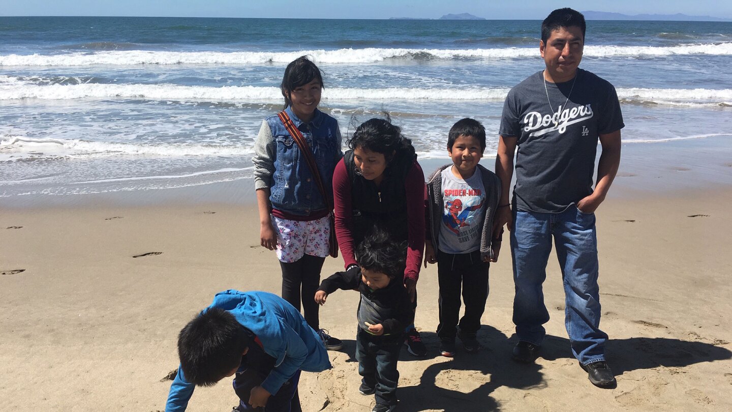 Tello family standing at the beach with Jordi (foreground), who is drawing a ninja in the sand. | Pilar Marrero