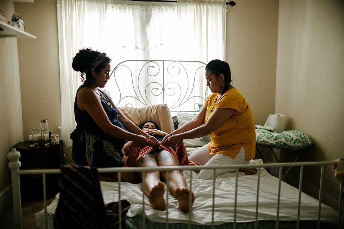 Panquetzani and her apprentice tie a rebozo around Kat Cardenas' pelvis. | Samanta Helou Hernandez
