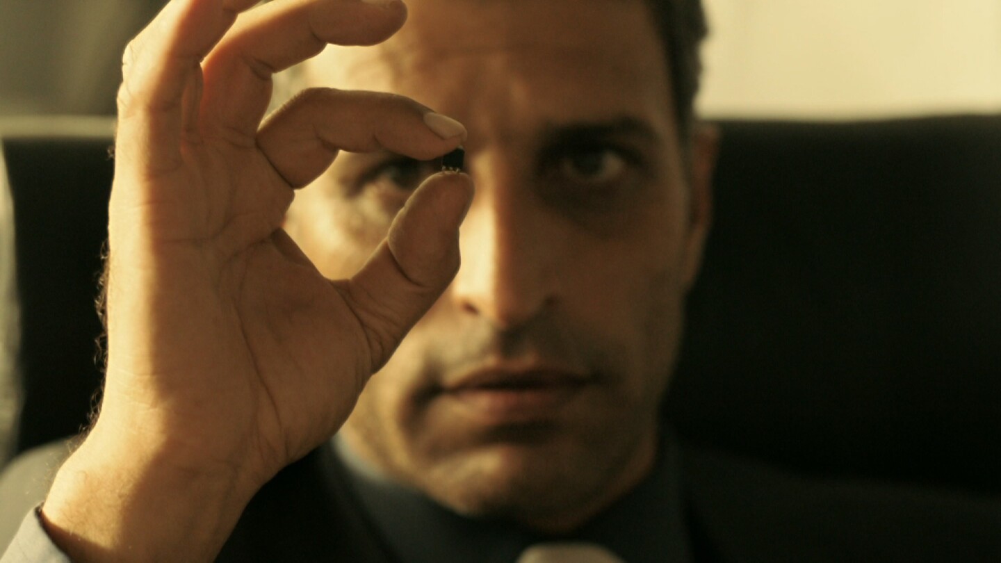 A man stares at something small held between his fingers from "Fauda: S2 E10."