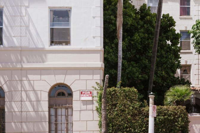 A small for rent sign hangs on a wall on the outside an apartment building in Koreatown. | Chava Sanchez/LAist