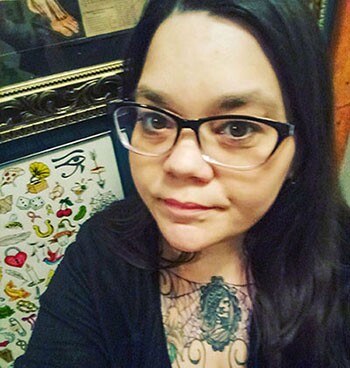 Bespectacled woman with long, black hair looks at camera