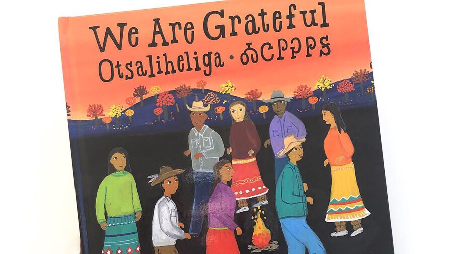 Book cover of “We Are Grateful: Otsaliheliga” by Traci Sorell and illustrated by Frané Lessac featuring colorful illustrations of people