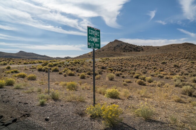 A desert landscape with a sign that says Coyote Summit.