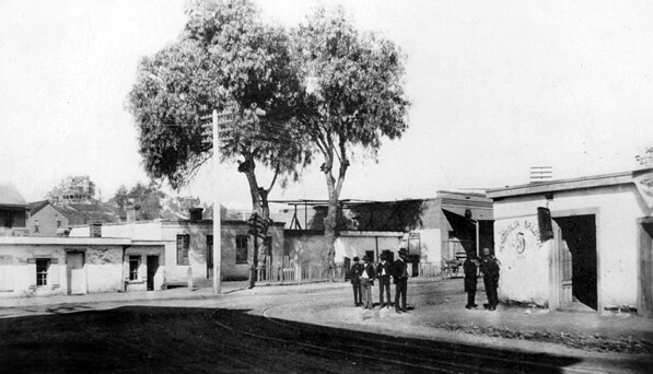 Men stand outside a Sonoratown saloon at Bellevue and Upper Main (now Spring), circa 1888. In the distance, the mansion of retail magnate J.W. Robinson sits atop Fort Moore Hill. Courtesy of the Los Angeles Public Library Photograph Collection.