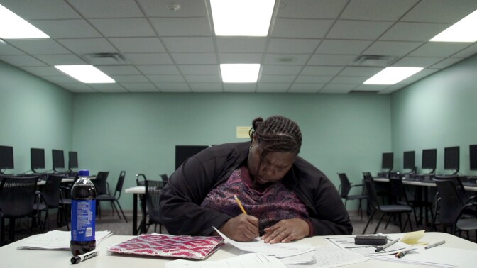 Night school student Melissa intently writes on a piece of paper in an empty computer lab. | From "Night School"