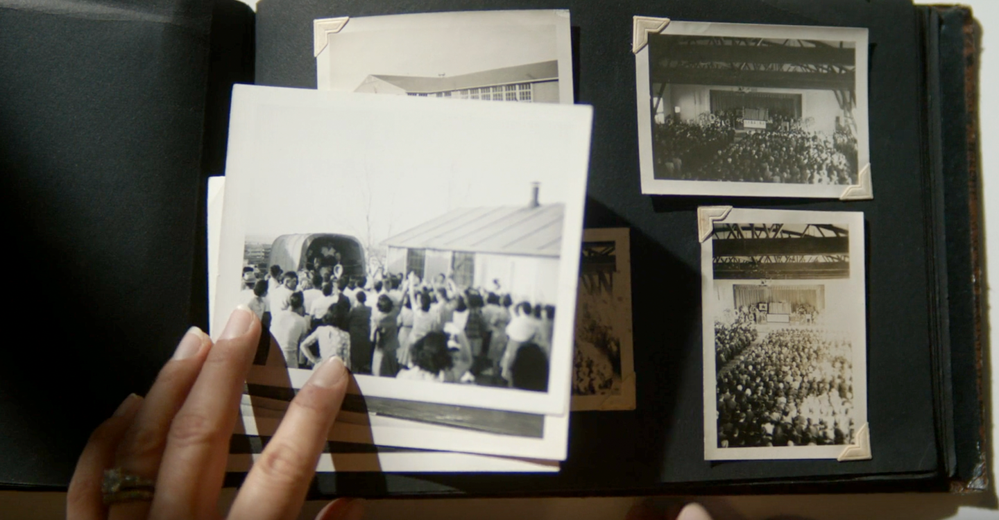 A person places their hand over a black and white photo rested on top of an open photo album.