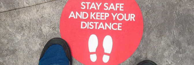 A sticker on the ground reads "Stay safe and keep your distance." | iStock